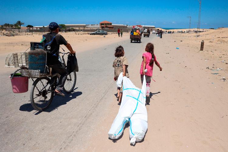 Palæstinensiske børn har samlet deres sager i en beskyttelsesdragt, som de slæber bag sig under flugt fra Tel al-Sultan-området ved Rafah i Gaza i krigen mellem Israel og Hamas. Foto: Eyad Baba/Ritzau Scanpix