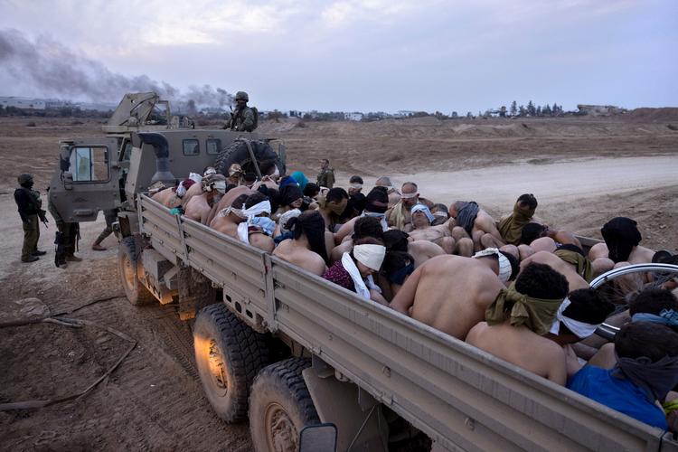 Israelske soldater bevogter palæstinensere, der delvis afklædte og med bind for øjnene er blevet placeret på ladet af en lastbil. Palæstinenserne er blevet taget til fange i Gaza. Foto: Moti Milrod/Ritzau Scanpix