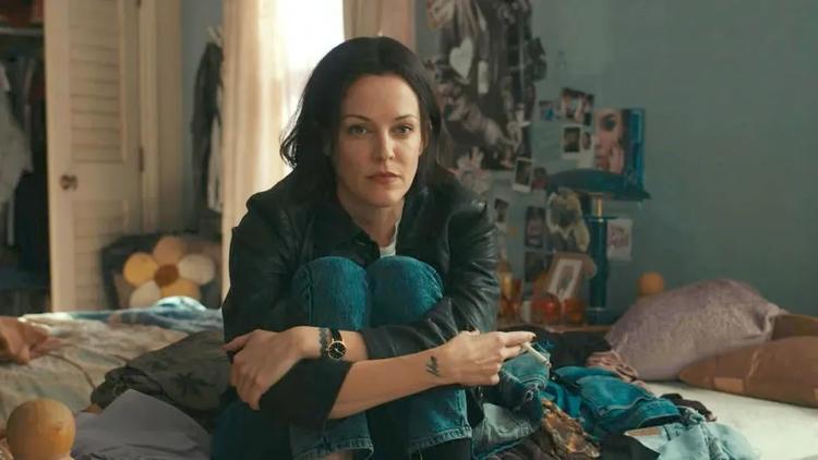 Riley Keough spiller hovedrollen som Rebecca Godfrey, der – måske – skriver en bog om mordet på Reena.  Foto: Disney+