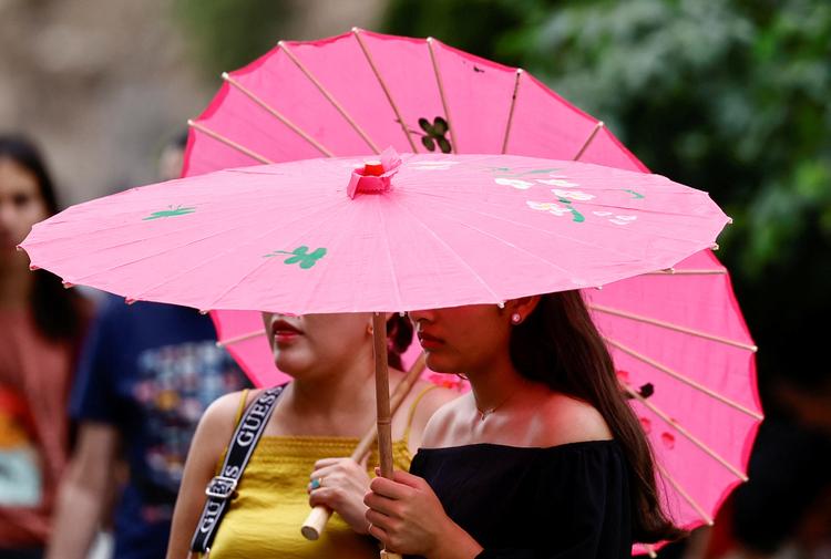 I store dele af Europa hærger en hedebølge. På billedet står turister foran turistattraktionen Colosseum i Rom og søger ly fra solen under deres paraplyer.  Foto: Yara Nardi/Ritzau Scanpix