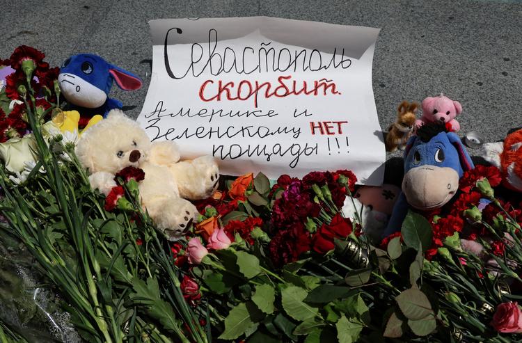 'Sevastopol sørger. Ingen nåde for USA og Zelenskyj', står der på et skilt ved et midlertidigt mindested for et angreb, der søndag kostede fire mennesker livet på Krim-halvøen. Foto: Alexey Pavlishak/Ritzau Scanpix
