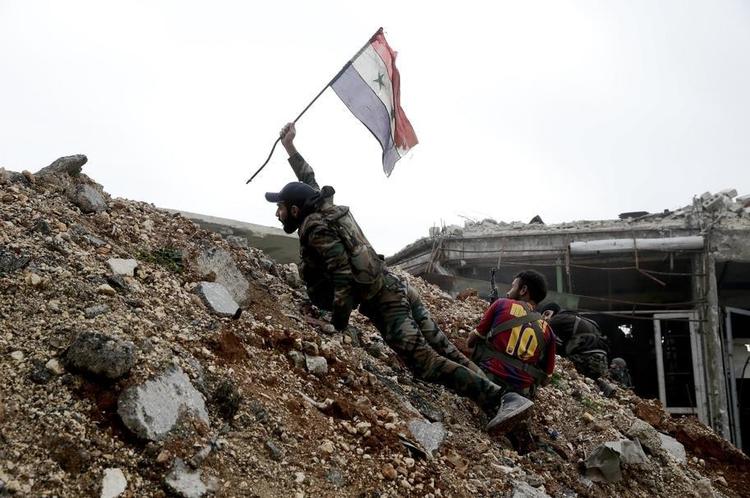 En soldat fra den syriske hær planter det nationale syriske flag ved en frontlinje i Østaleppo. 