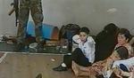 Fra gymnastiksalen i Beslan. En russisk skoledreng med foden på en mekanisme, der kan udløse en bombe. Arkivfoto: AP / NTV (russisk tvkanal)  