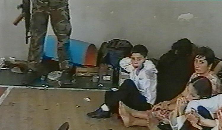 Fra gymnastiksalen i Beslan. En russisk skoledreng med foden på en mekanisme, der kan udløse en bombe. Arkivfoto: AP / NTV (russisk tvkanal)  