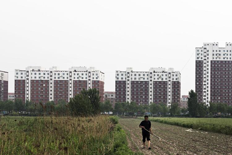 En landmand går på sin mark uden for den nuværende by Rongchen. Om få år vil hele området være omdannet til en ny kæmpeby. 
