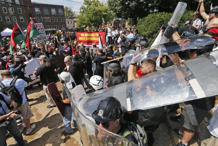 En gruppe hvide demonstranter brugte skjolde til at beskytte sig med, da de lørdag stødte sammen med en moddemonstration ved indgangen til Lee Park i Charlottesville. 