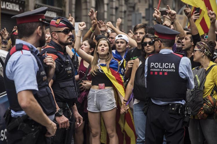 Politifolk fra lokalpolitiet Los Mossos sammen med vælgere søndag. Nu risikerer politiets ledelse sigtelse med risiko for 15 års fængsel for ikke have deltaget i forsøgene på at hindre den ulovlige folkeafstemning. 
