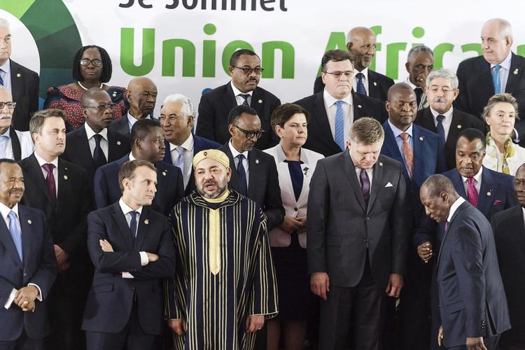 Frankrigs præsident, Emmanuel Macron, lytter med korslagte arme til Marokkos kong Mohammed VI, under et gruppefoto på topmødet mellem Europa og Afrika. 