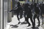 En aktivist sparker til  vinduet ind til et forsikringsselskab under demonstrationer i april til støtte for  jernbaneansatte.   Francois Mori/AP