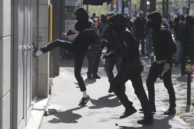 En aktivist sparker til  vinduet ind til et forsikringsselskab under demonstrationer i april til støtte for  jernbaneansatte.   Francois Mori/AP