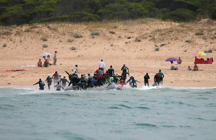 Mange migranter når over Middelhavet. Her løber en gruppe op på stranden blandt turister nær Tarifa i Andalusien. Foto: Jon Nazca/Ritzau Scanpix /Ritzau Scanpix