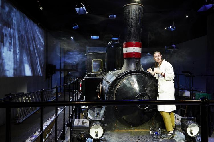 Damplokomotivet, der er hejst ned, før der blev lagt tag på den underjordiske attraktion, bliver vartegn for den permanente udstilling, ’Aarhus Fortæller’. Det var jernbanen, der sammen med kysthavnen gjorde, at Aarhus pludselig voksede og blev provinsens største. Udstillingen fortæller byhistorie gennem både klassiske scenarier med vikingehytter og handelsstationer og digitale touch screens, og publikum kan gå på jagt efter detaljer og erindringer i en række små skabe med mini-tableauer. Og så har Den Gamle By skabt et nyt hjørne, viet til Aarhus som musikby. 