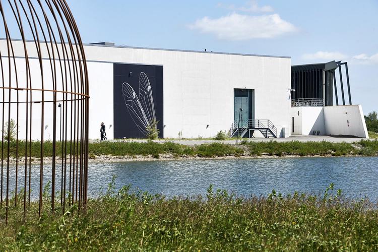 Et blik over mod den kunstige museumsø med Arkens mure – og Nanna Debois Buhls store foto af en skrøbelig insektvinge. 