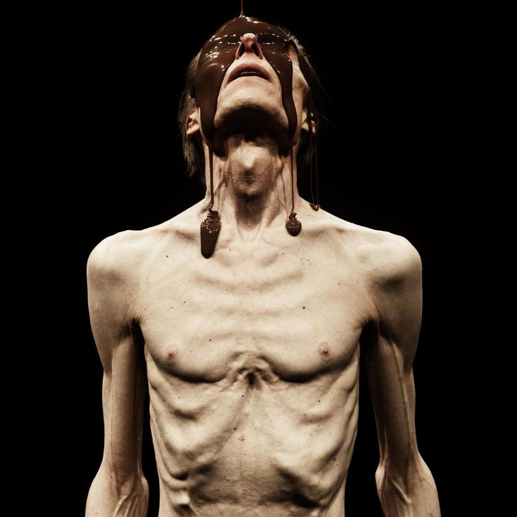 I opsætningens slutbillede står Madame Nielsens nøgne hvide krop til fuld skue foran publikum. Anorektisk afpillet til skind og ben, mens den overmales  af en chokoladeglinsende brun stråle – og ikke mindst alskens racepolitiske værditilskrivninger.   Foto Sofie Klougart.