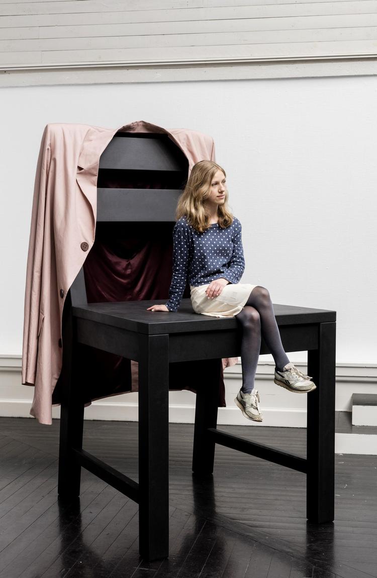 Peter Holst Henkels værk ’Voksenhed forklaret for børn’ fra 2018 er en gigantisk stol med en lige så gigantisk jakke hængende over stoleryggen. På jakken er printet fotos af hænder, som enten beskytter eller afstraffer. Anders Sune Berg