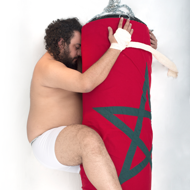 Performancekunstneren Youssef Ouchra i en intim omfavnelse af en boksebold. Foto Youssef Ouchra
