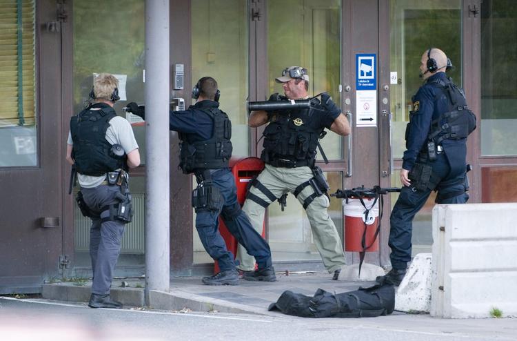 Politiet forsøger at komme ind i G4S’ værdidepot, hvorfra tre mænd stjal 39 millioner svenske kroner. Men de var fløjet, med helikopter.   Pontus Lundahl/AP