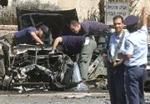 Politibetjente kigger på vraget af den eksploderede bil i Jerusalem. - Foto: AP 