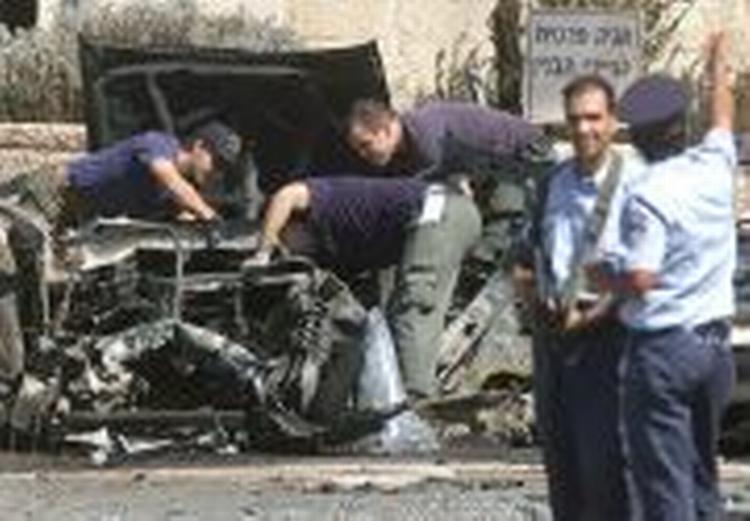 Politibetjente kigger på vraget af den eksploderede bil i Jerusalem. - Foto: AP 