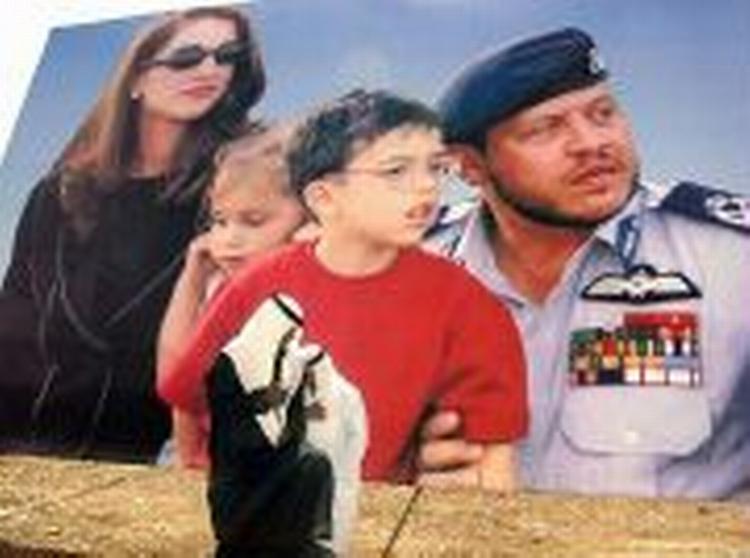 To jordanske mænd foran en kæmpeplakat med landets kongefamilie. - Foto: AP 
