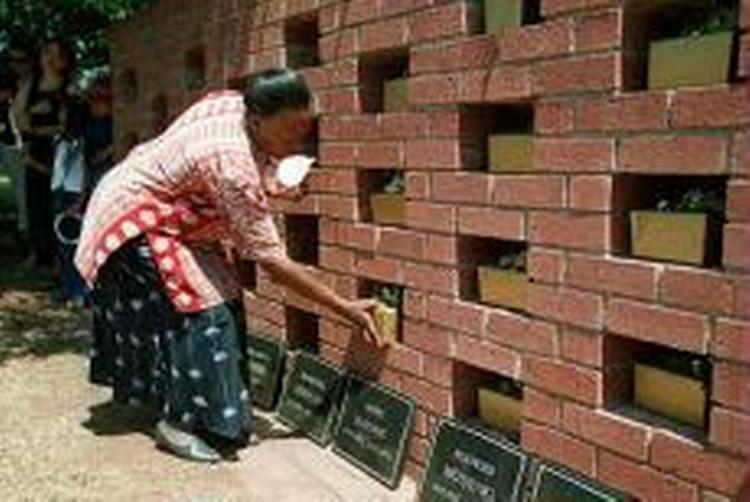 En sydafrikansk ansat på et børnehjem placerer asken af 17 kremerede spædbørn, alle døde af aids. - Foto: AP 