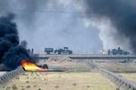 En amerikansk militærkonvoj passerer en brændende olierørledning nær Iraks næststørste by, Basra. - Foto: AP 