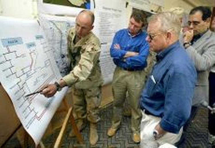 Jay Garner (blå skjorte og solbriller) får her en briefing om Bagdads elforsyning af en amerikanske ingeniør. Garner har ikke mange venner i den arabiske verden. - Foto: AP 