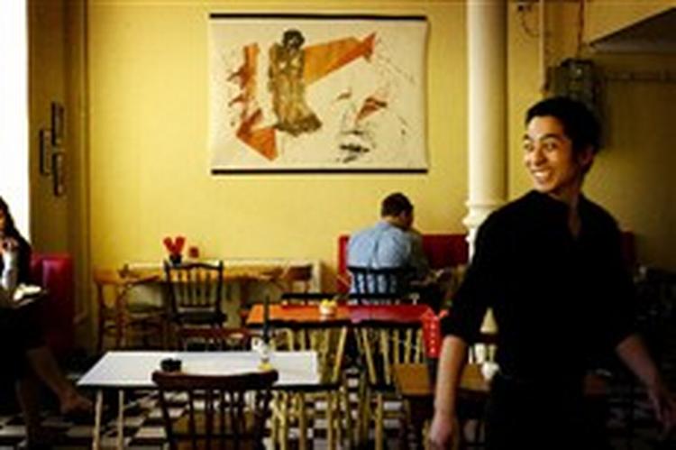 Atmosfæren i Lê Lê nhà hàng er som i en neoklassisk parisercafé, med umage borde og stole, højt til loftet og hurtig, venlig betjening. Her er Lam Le Hoang på vej igennem restauranten. - Foto: Miriam Dalsgaard. 