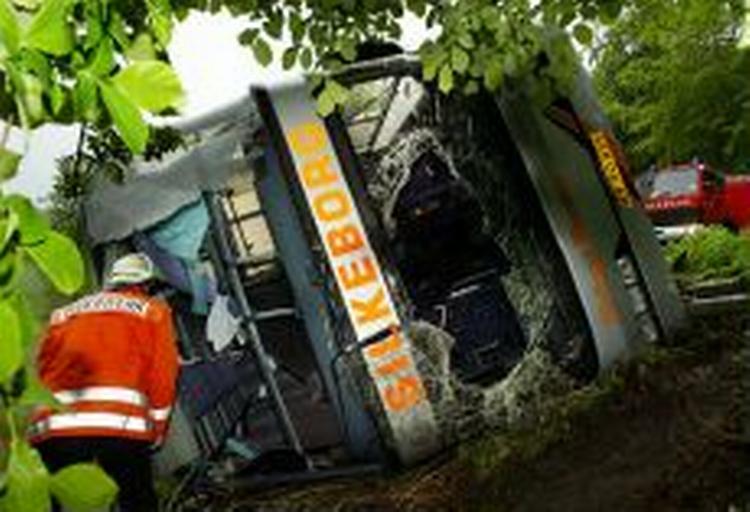 Redningsfolk undersøger den væltede bus. - Foto: AP 