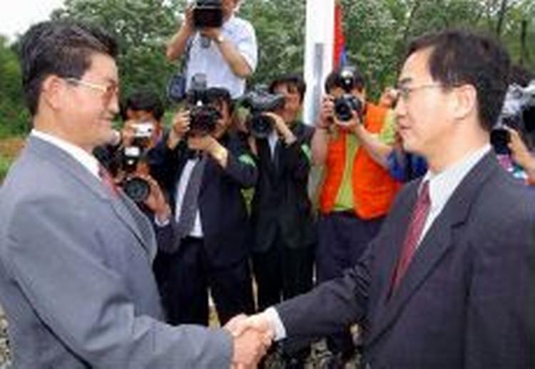 Den nordkoreanske delegerede, Byung Chul (tv), hilser på sin sydkoreanske kollega Myong-kyun. Den nordkoreanske herre ønskede en større fest, men måtte nøjes med et håndtryk. - Foto: AP 