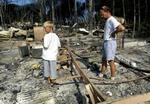 To turister ser på resterne af deres campingvogn, der udbrændte i byen Trejus. - Foto: AP 