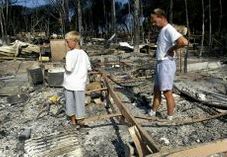 To turister ser på resterne af deres campingvogn, der udbrændte i byen Trejus. - Foto: AP 