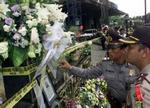 Indonesiske betjente ser på billeder af ofrene for bombesprængningen i Jakarta. - Foto: AP 