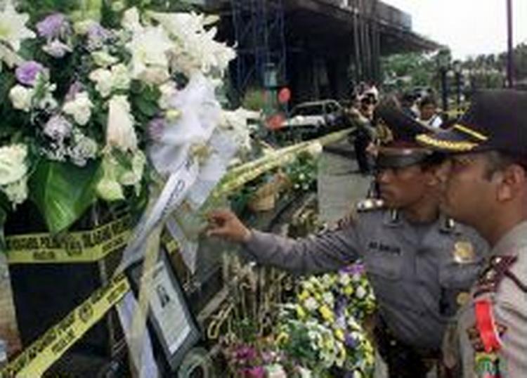 Indonesiske betjente ser på billeder af ofrene for bombesprængningen i Jakarta. - Foto: AP 