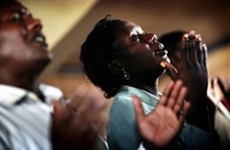 NÅDE Midt i gudstjenestens kaos af musik, gospelsang, højlydte lovprisninger og bekendelser lukker Esther sig en stor del af tiden inde i sin egen verden. Til venstre hendes mand Michael. - Foto: Thomas Borberg 