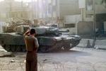 En irakisk dreng ser en amerikansk tank køre forbi en vejspærring i Bagdad. - Foto: AP 