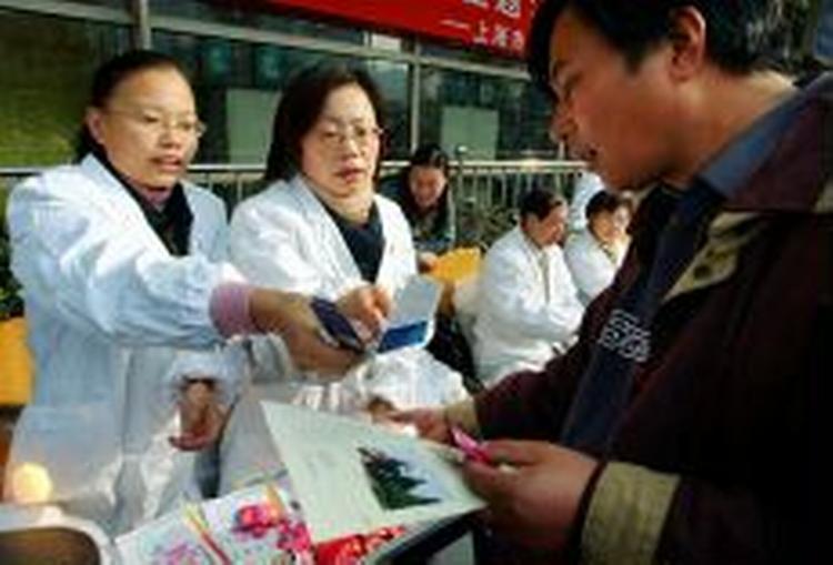 Kinesisk sundhedspersonale deler materiale ud i Shanghai. - Foto: AP 