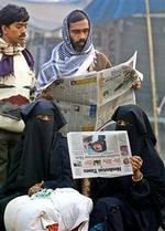 Muslimske kvinder og andre læser ved et busstoppested i Allahabad i Indien om Saddam Husseins tilfangetagelse. Over hele verden var hans foto på forsiderne.   Foto: Rajesh Kumar Singh/AP Photo 