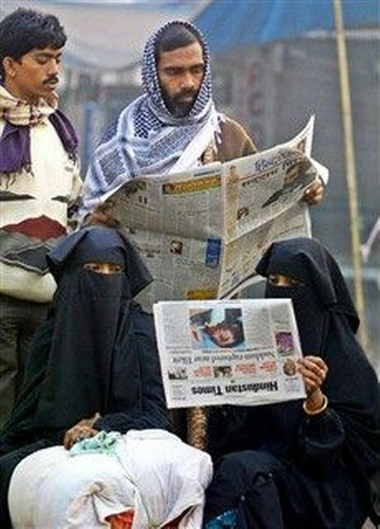 Muslimske kvinder og andre læser ved et busstoppested i Allahabad i Indien om Saddam Husseins tilfangetagelse. Over hele verden var hans foto på forsiderne.   Foto: Rajesh Kumar Singh/AP Photo 