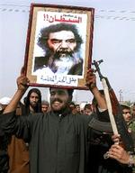 Medlemmer af den proiranske al-Da wa parti fejrer Saddam Husseins tilfangetagelse. Over billedet står  Djævlens fald . Nedenunder  De sorte hullers helt .   Foto: Nabil Aljurani/AP 