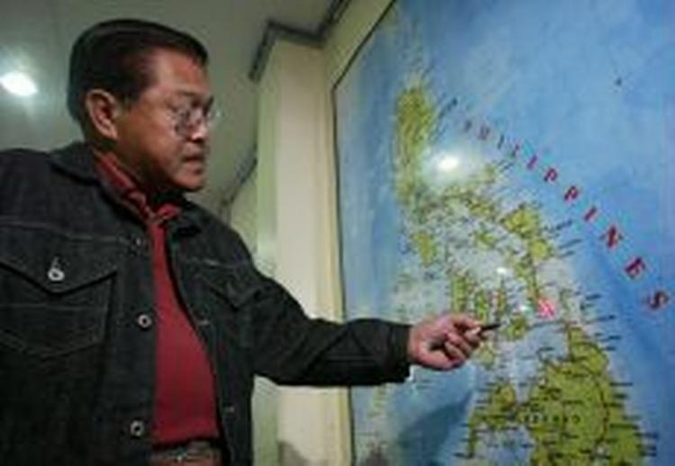 Med en laser peger en filippinsk embedsmand på et kort, hvor jordskredet skete. - Foto: AP 