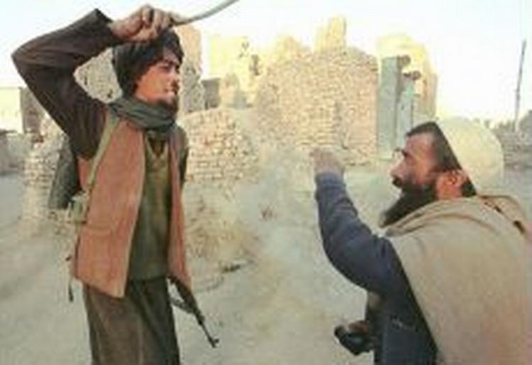En civil afghaner får tæv af en talebaner for at være i besiddelse af opium. - Arkivfoto: AP 