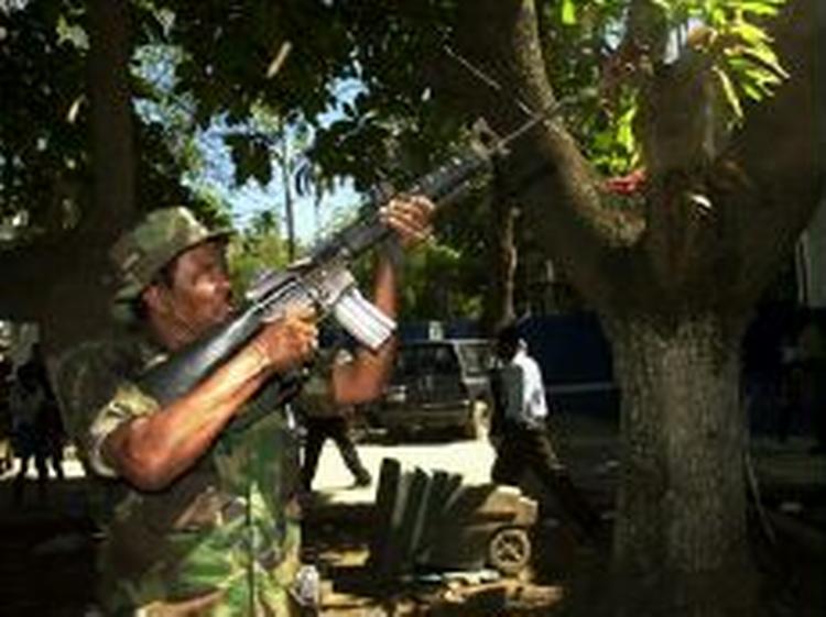 Oprørslederen Chamblain affyrer et par skud til ære for fotografen under indtagelsen af havnebyen Cap Haitien i går. - Foto: AP 