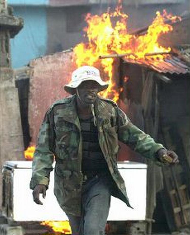 Haitansk oprører sætter ild på mistænkt Aristide-tilhængers hus i Haitis næststørste by, Cap Haitien. - Foto: AP 