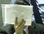 Marc Dutroux gemte sit ansigt bag papirer. - Foto: AP 