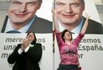 To tilhængere i Pamplona fejrer PSOE's sejr foran en plakat forestillende partileder Zapatero. - Foto: AP 