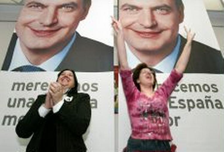 To tilhængere i Pamplona fejrer PSOE's sejr foran en plakat forestillende partileder Zapatero. - Foto: AP 