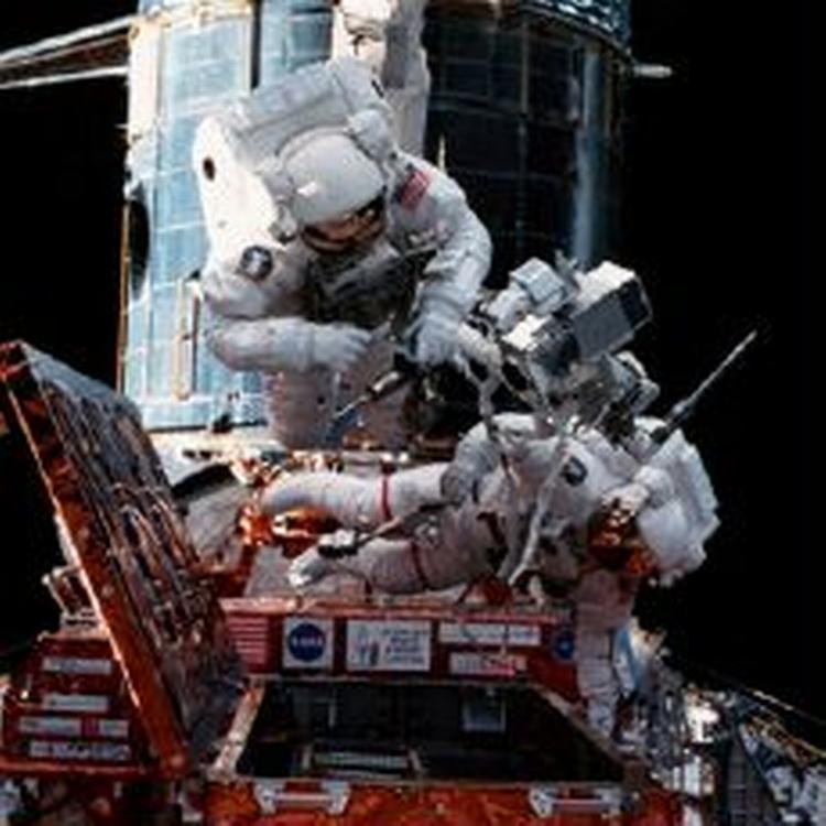 To astronauter reparerer på Hubble rum-teleskopet ude i rummet. Nu vil astronauterne kæmpe for Hubbles liv. - Arkivfoto: Spacephotos.com 