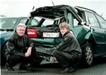 Et par af Volvos sikkerhedseksperter ved en bil, der er ramt bagfra. Denne type uheld kan mildnes med den nye elektroniske nødbremse fra Volvo. 