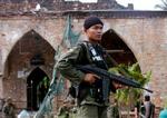 En thailandsk politimand bevogter en moske i Pattani-provinsen i den sydlige del af landet. 32 militante oprørere mistede livet, da sikkerhedsstyrker stormede moskeen. - Foto: AP 